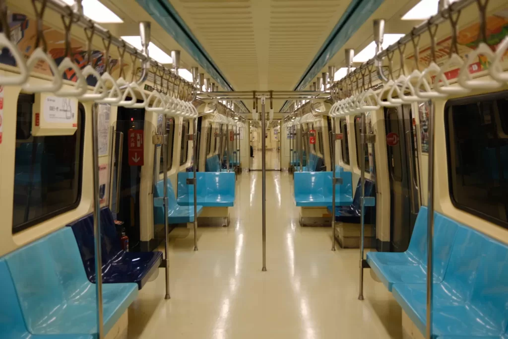 Interior of a Taipei MRT train with rows of seating and handlebars for standing passengers.